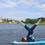 Com'etic a réalisé la refonte du site de cours de Yoga ashtanga en salle à douarnenez et en ligne par Aude, professeur de yoga certifié. Aude Chancerelle effectuant une posture de yoga Ashtanga sur un paddle