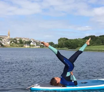 Com'etic a réalisé la refonte du site de cours de Yoga ashtanga en salle à douarnenez et en ligne par Aude, professeur de yoga certifié. Aude Chancerelle effectuant une posture de yoga Ashtanga sur un paddle